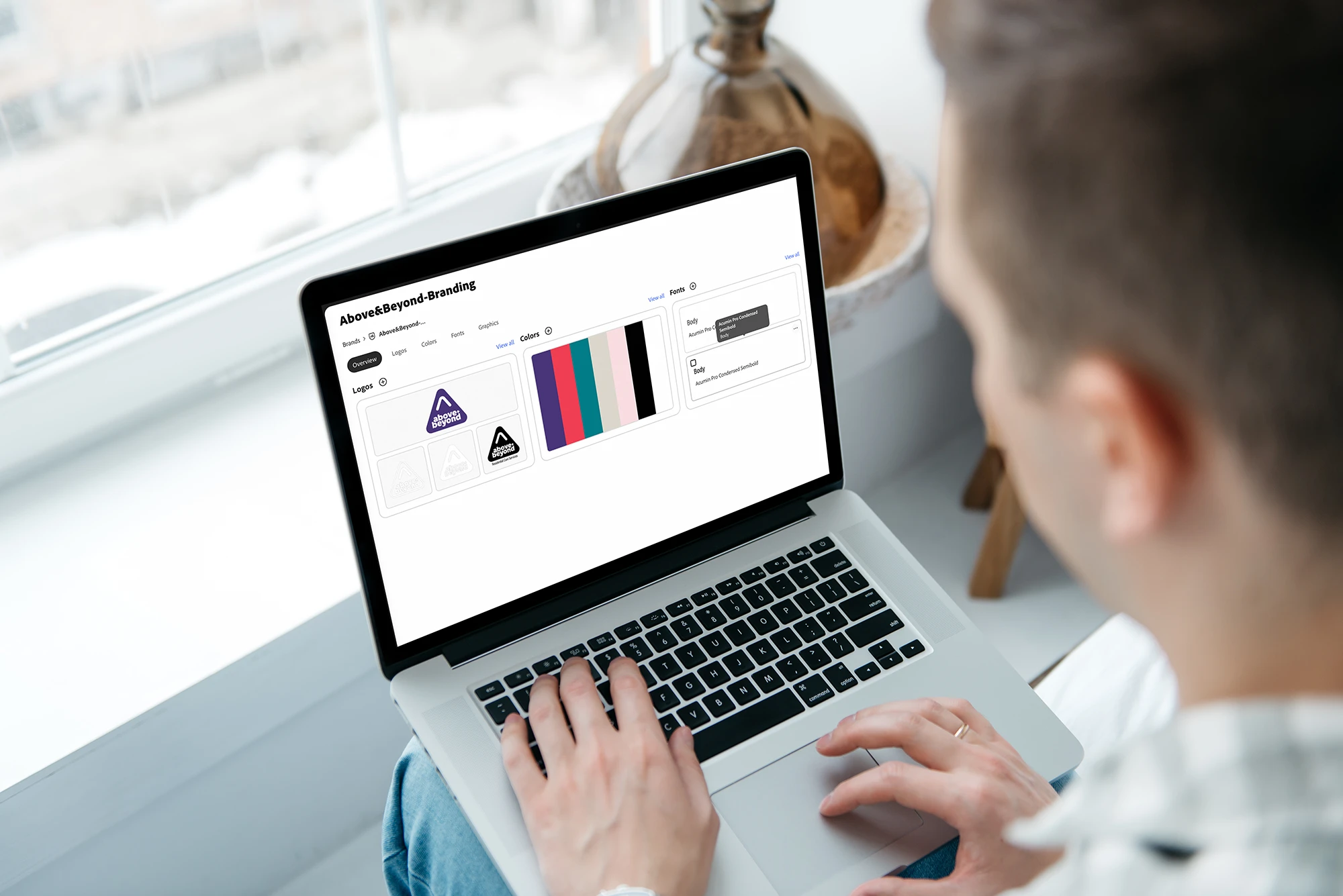 Person working on a laptop displaying a branding and colour palette design.