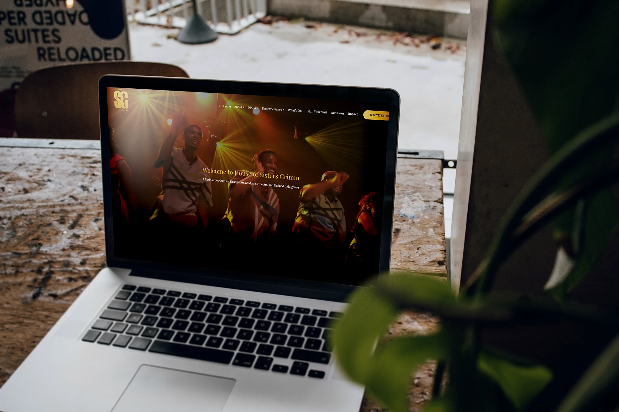 Laptop displaying the House of Sisters Grimm website on a wooden table.