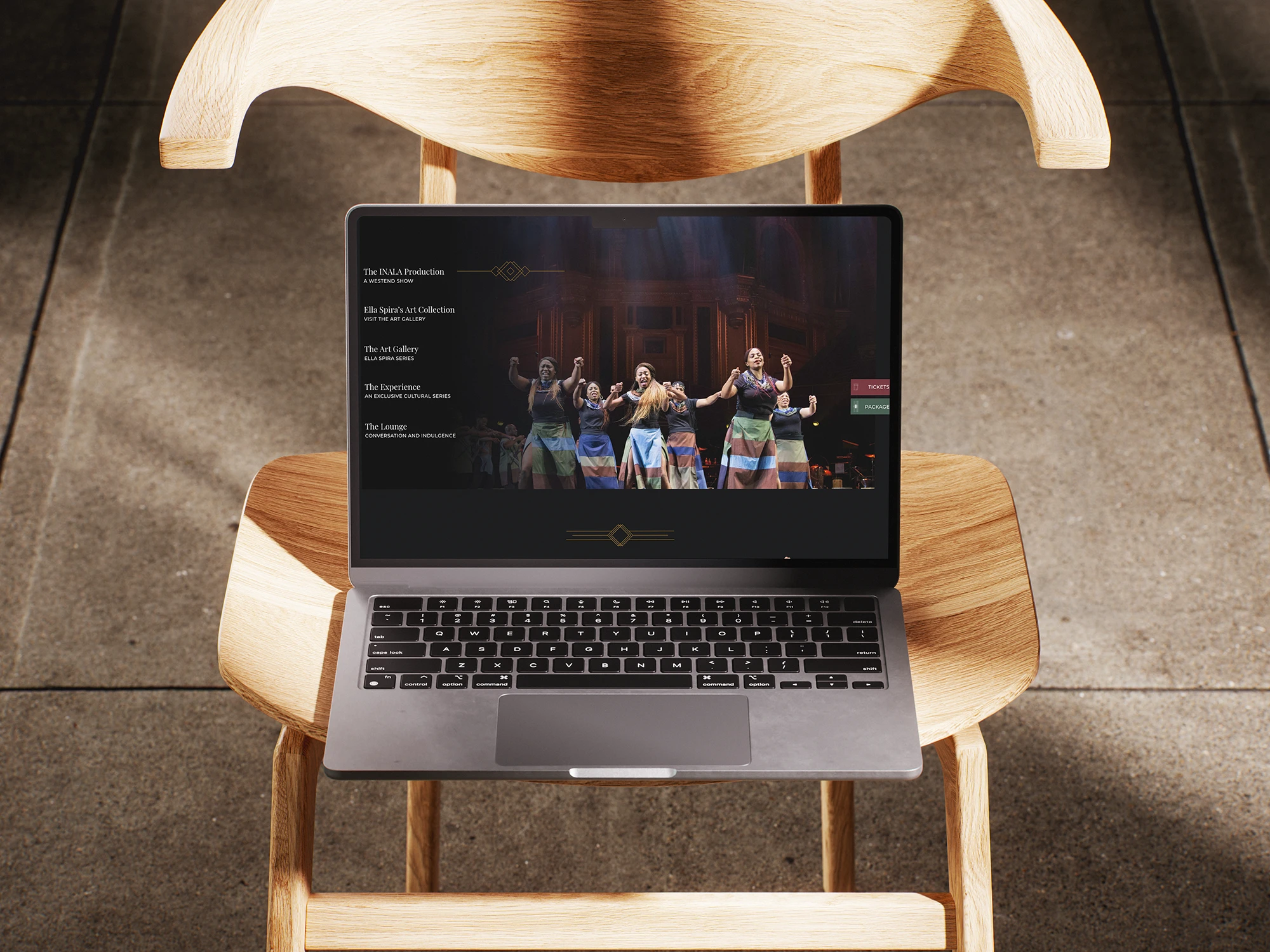 Laptop on wooden chair displaying a dance performance website for House of Sisters Grimm.