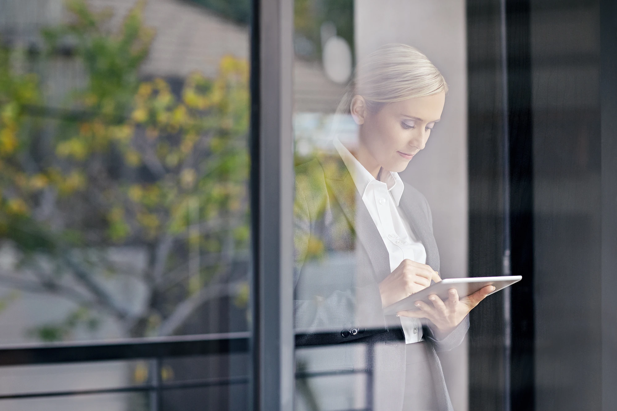 Businesswoman using a tablet outside an office building during maintenance and monitoring activities.